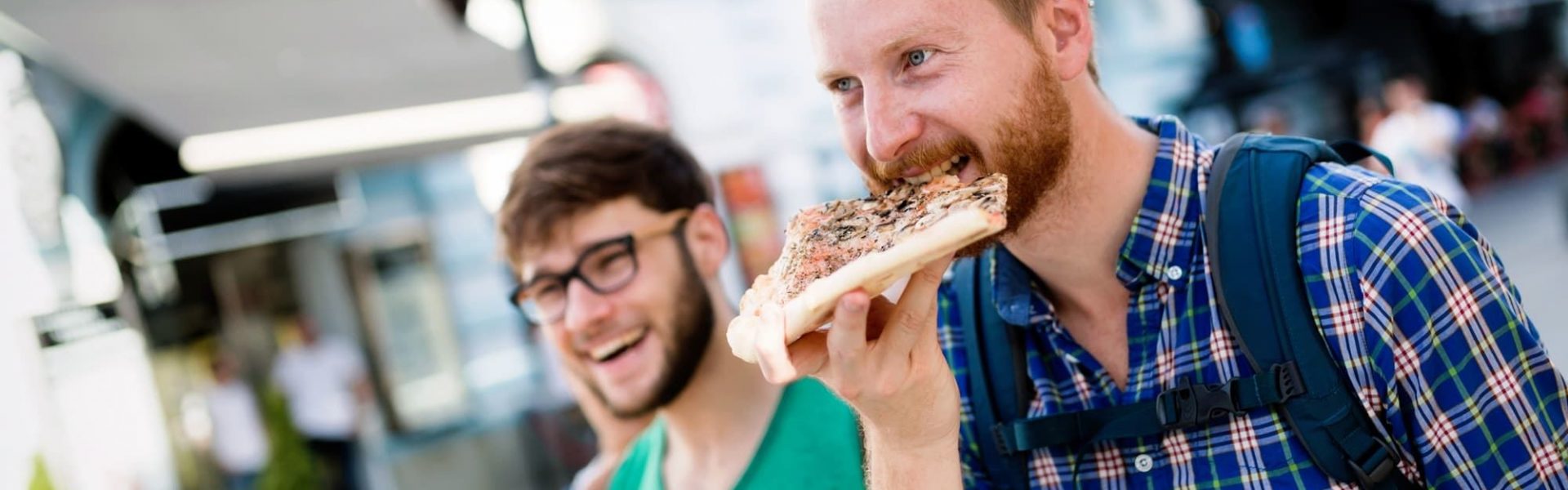 Happy students eating pizza on street